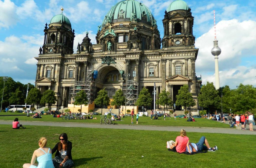 Pessoas sentam no gramado em frente à Catedral de Berlim