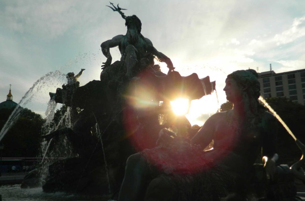 Luz do pôr do sol ilumina as figuras de ferro fundido da fonte Neptunbrunnen