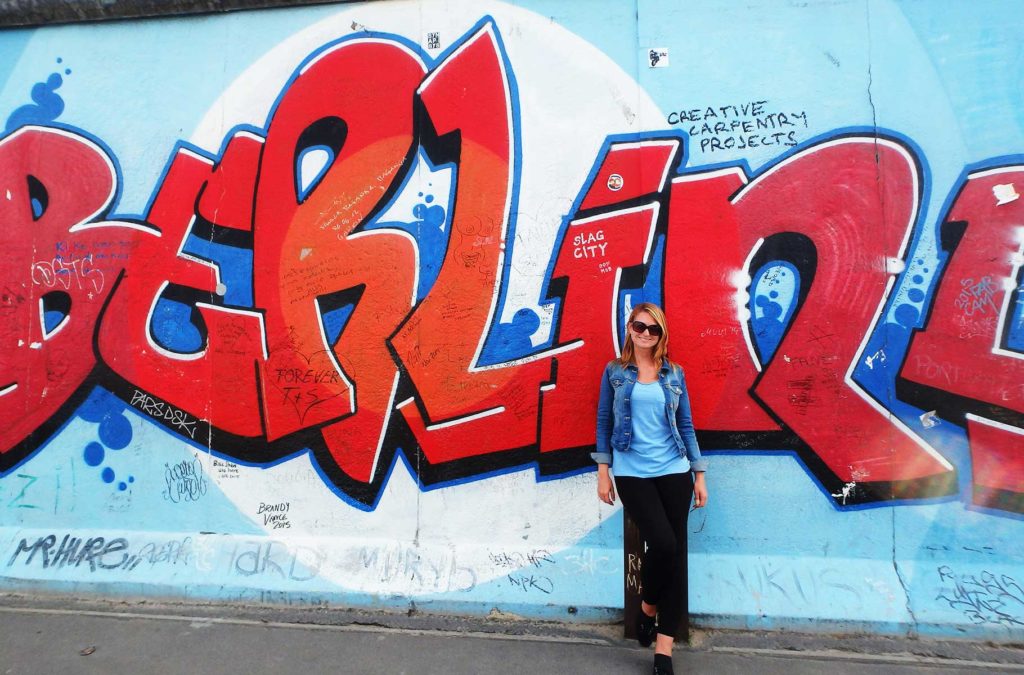 Turista posa em frente ao trecho do Muro de Berlim conhecido como East Side Gallery