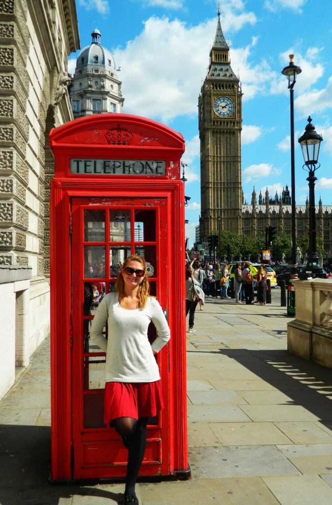 Turista posa para foto em uma cabine telefônica vermelha de Londres com o Big Ben ao fundo