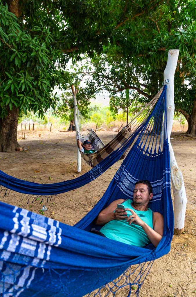 Turista descansa em redário com o celular na mão