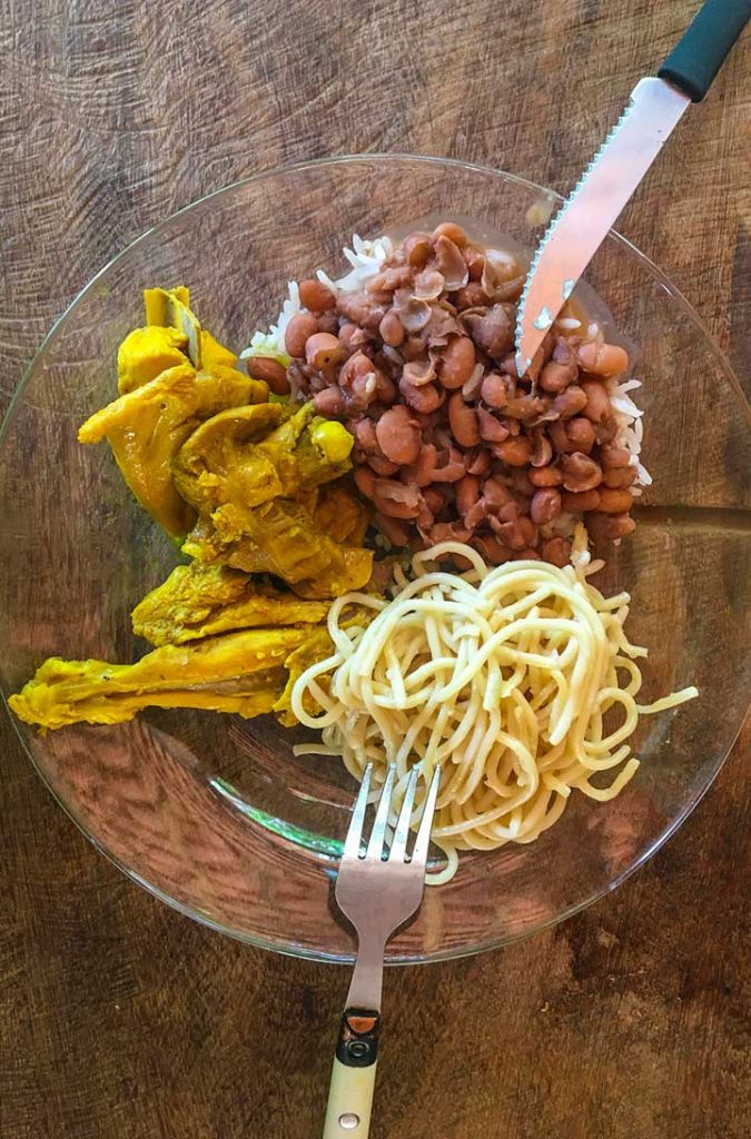 Prato de comida caseira com massa, arroz, feijão e frango caipira