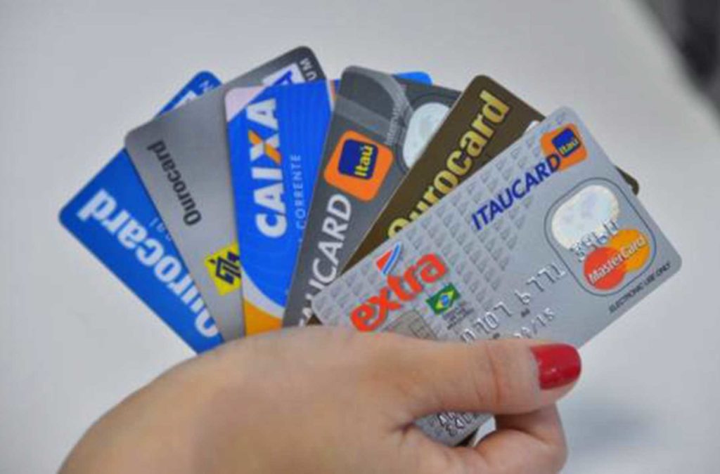Mulher segura vários cartões de crédito na mão