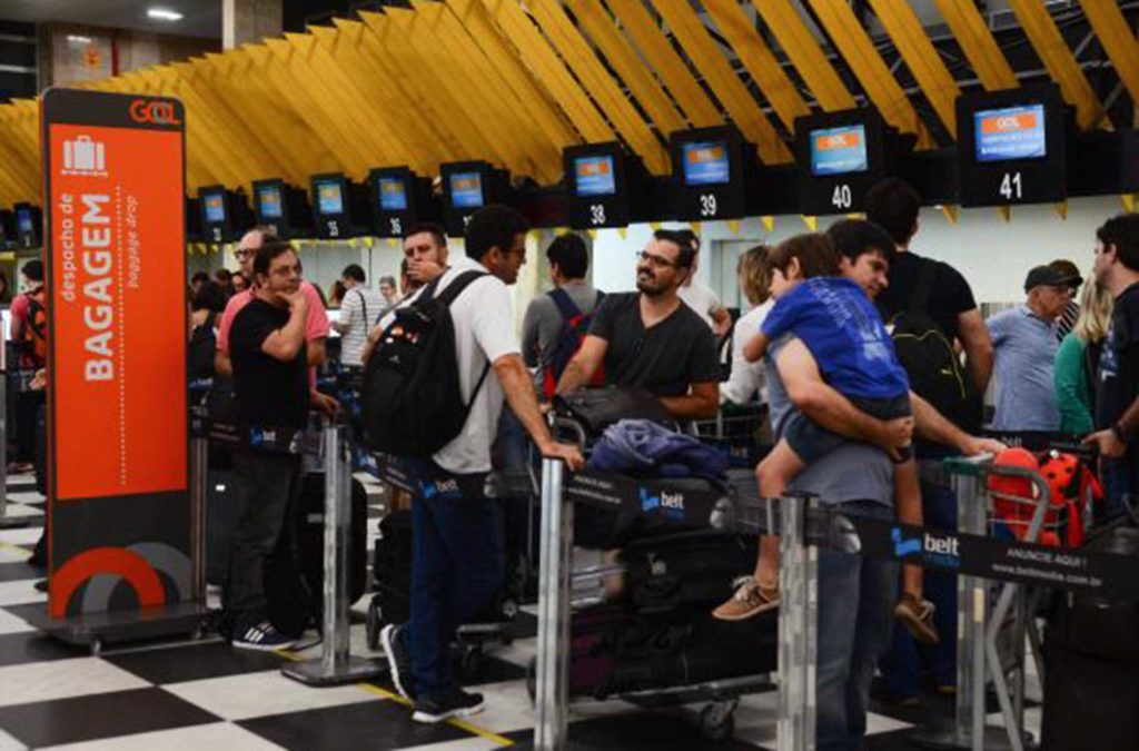 Pessoas fazem fila para fazer chec in no balcão de atendimento de aérea em aeroporto