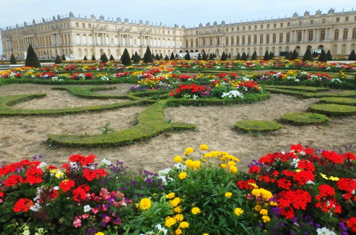 Canteiros floridos com o Palácio de Versalhes ao fundo