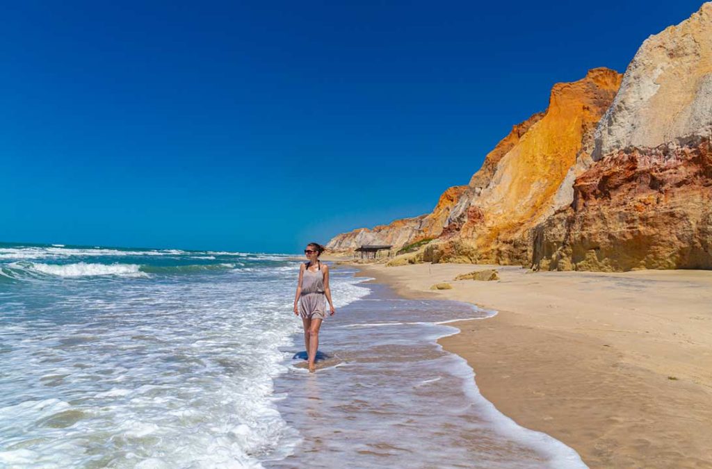 Mulher caminha próxima das falésias da Praia de Morro Branco