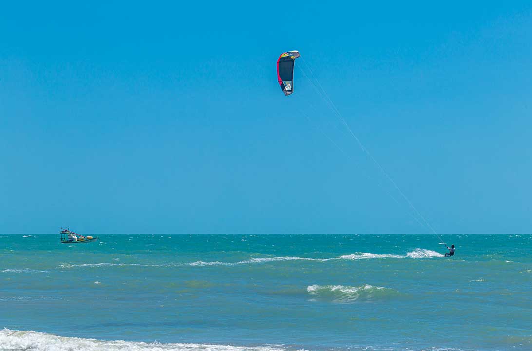 Pessoa pratica kitesurf no mar na praia de Canoa Quebrada