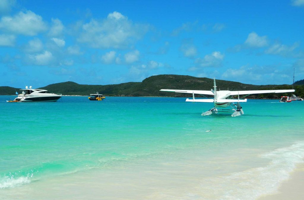 Hidroavião e barcos flutuam no mar na beira da praia de Whitehaven