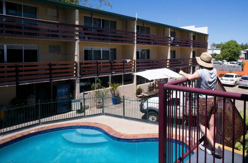 Mulher olha para a piscina de hostel em Airlie Beach