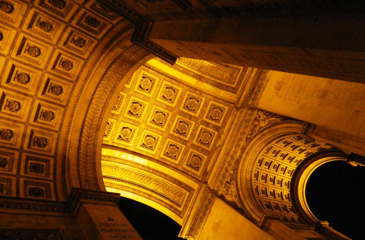 Parte inferior do Arco do Triunfo iluminada à noite, em Paris