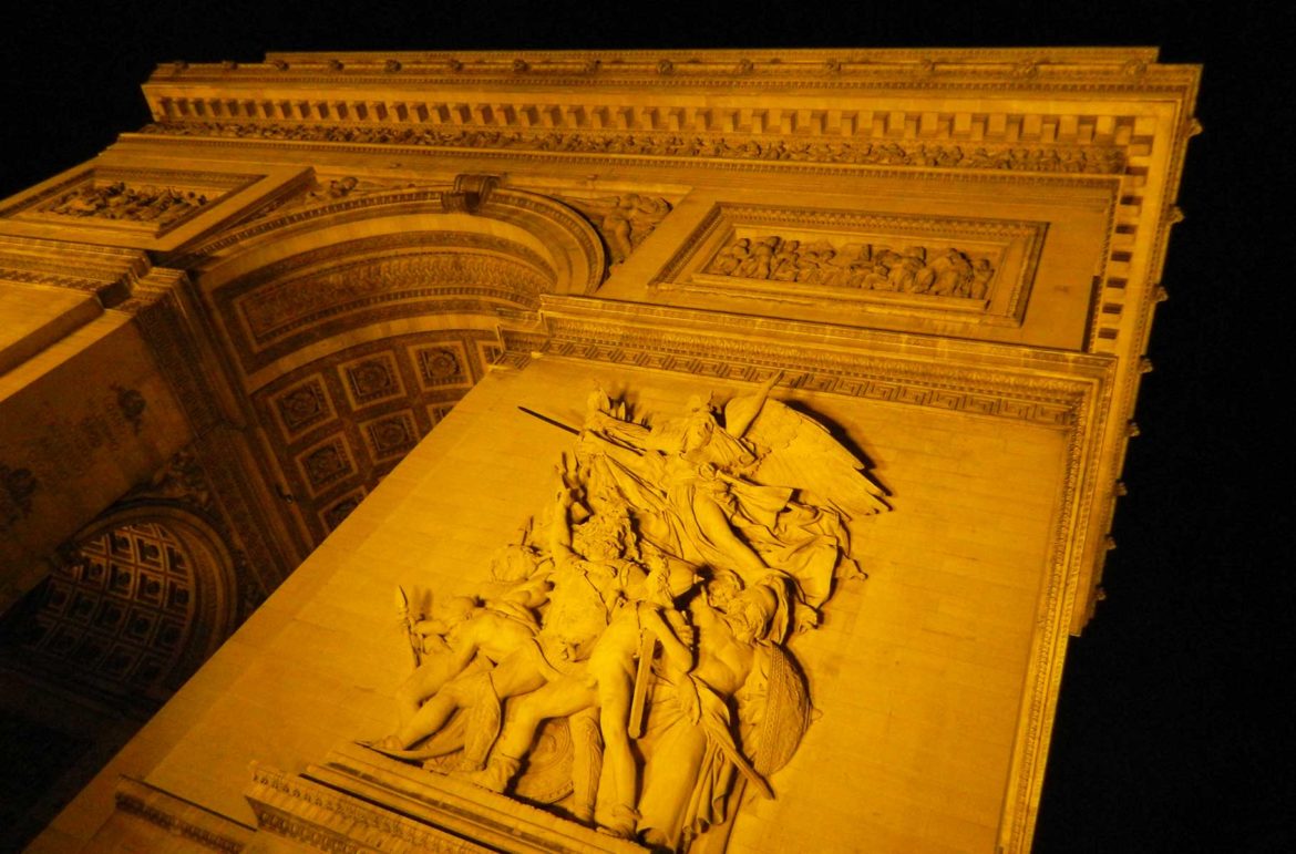 Fachada do Arco do Triunfo iluminada à noite, em Paris