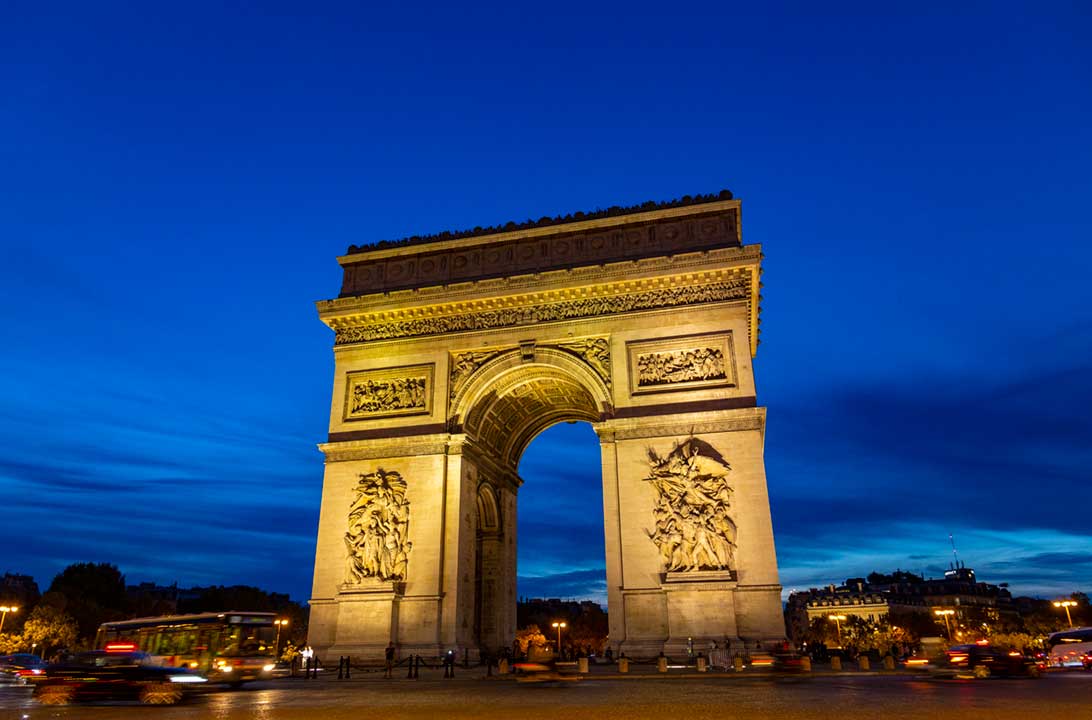 Arco do Triunfo iluminado ao anoitecer, em Paris