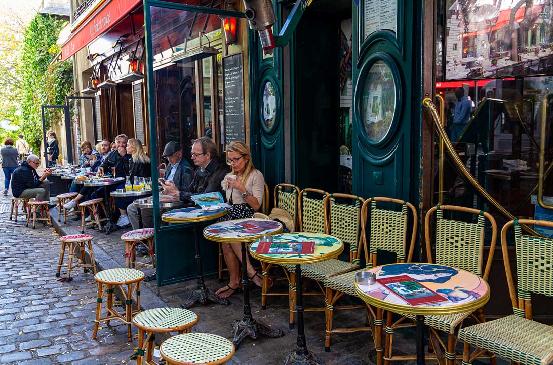 Pessoas sentam na mesa de um café no bairro de Montmartre, em Paris