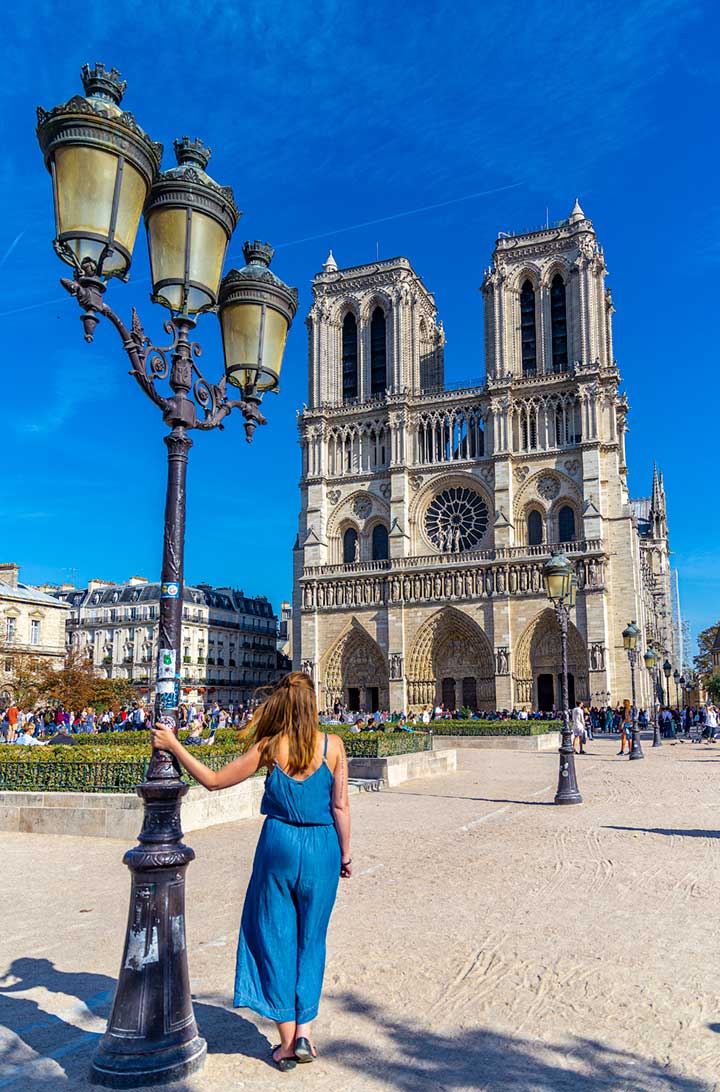 Mulher posa para foto na praça em frente à Catedral de Notre-Dame, em Paris
