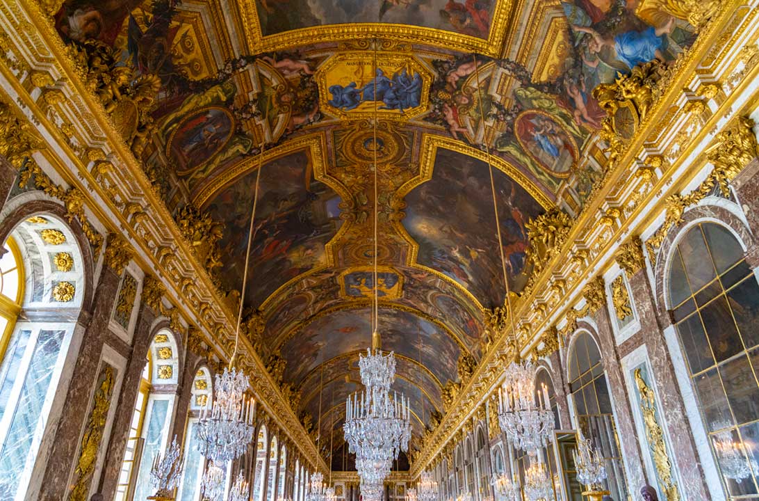 Candelabros e afrescos no teto do Salão dos Espelhos do Palácio de Versalhes