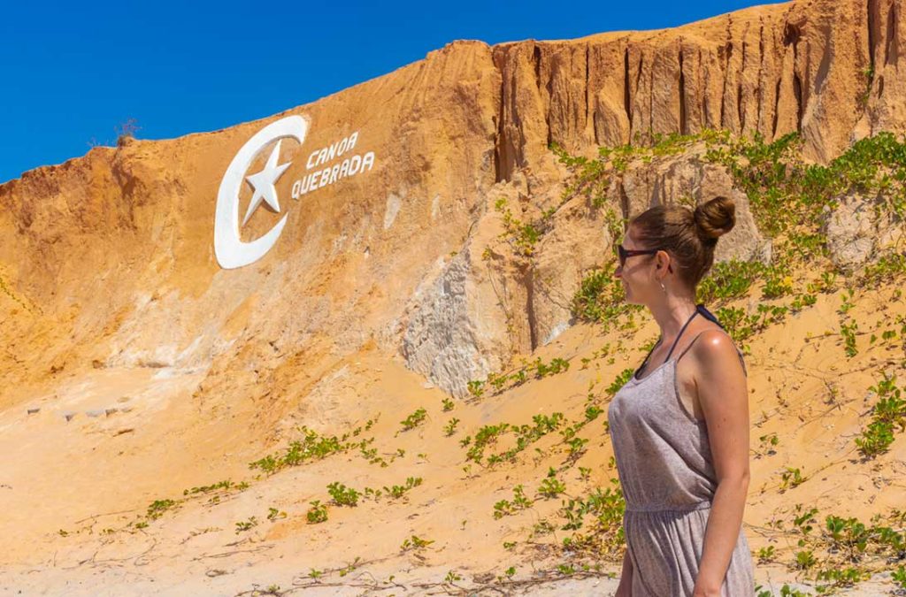 Mulher olha para o símbolo de Canoa Quebrada nas falésias da praia