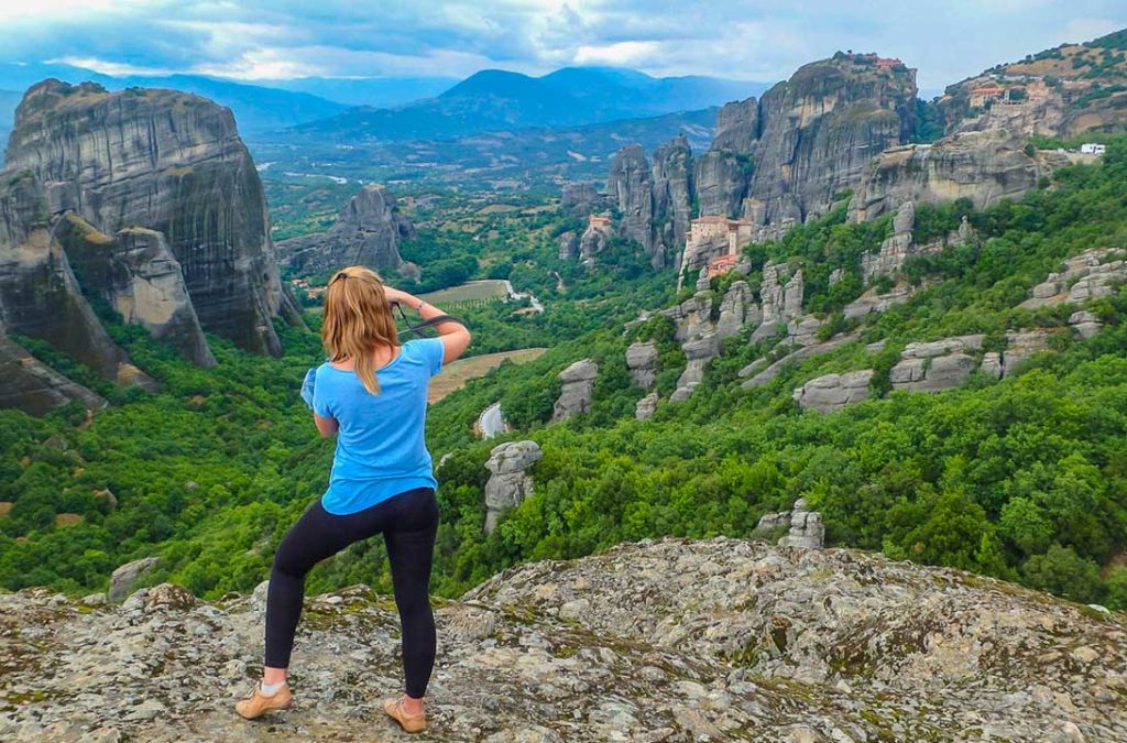 Mulher tira fotos da paisagem vista desde o primeiro mirante da rodovia dos Mosteiros de Meteora