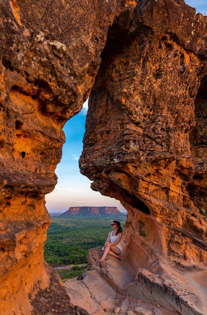 Mulher admira o pôr do sol no Portal da Chapada das Mesas