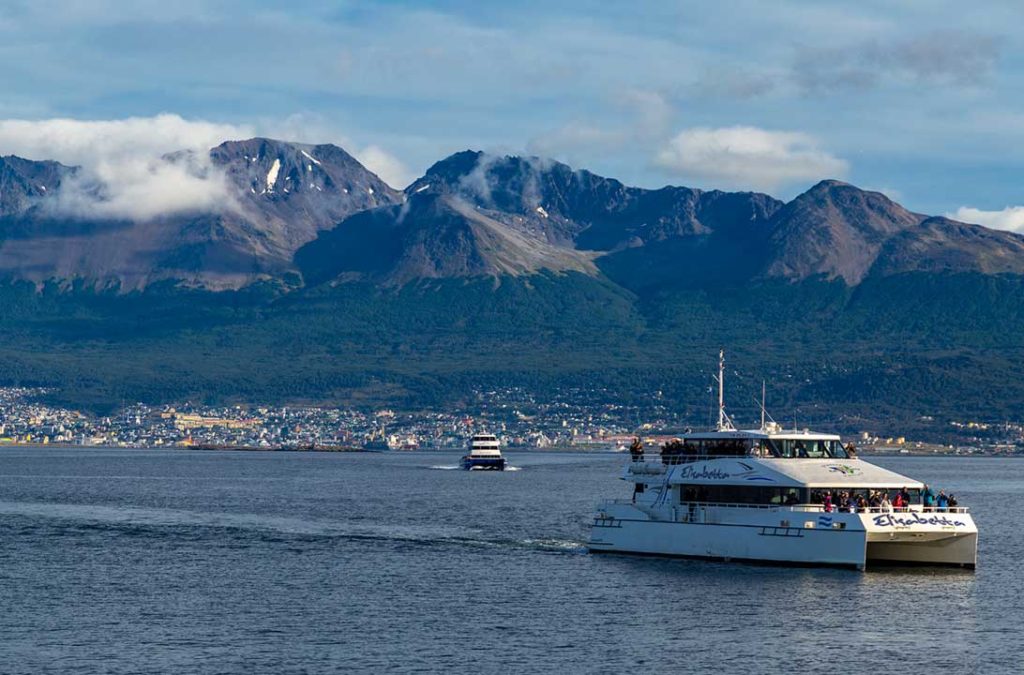 Catamarãs levam turistas para navegação pelo Canal de Beagle, com Ushuaia ao fundo