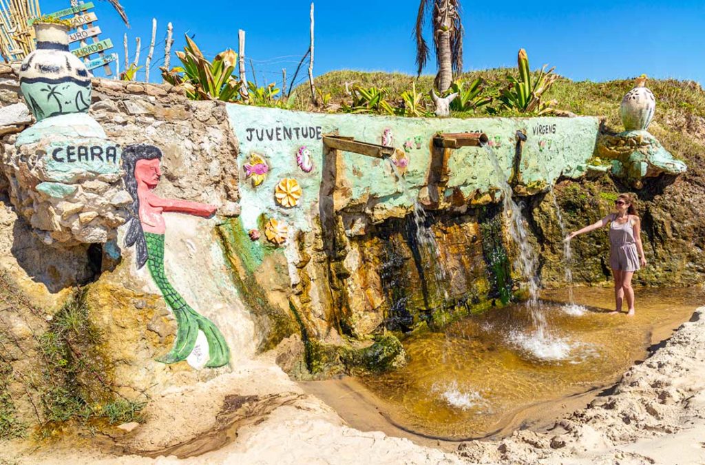 Mulher molha a mão na Fonte da Juventude, na Praia das Fontes