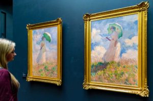 Visitante admira os quadros Mulher com Guarda-sol, de Claude Monet