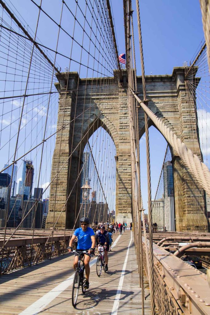 Ciclistas passam pelos arcos de pedra da Brooklyn Bridge