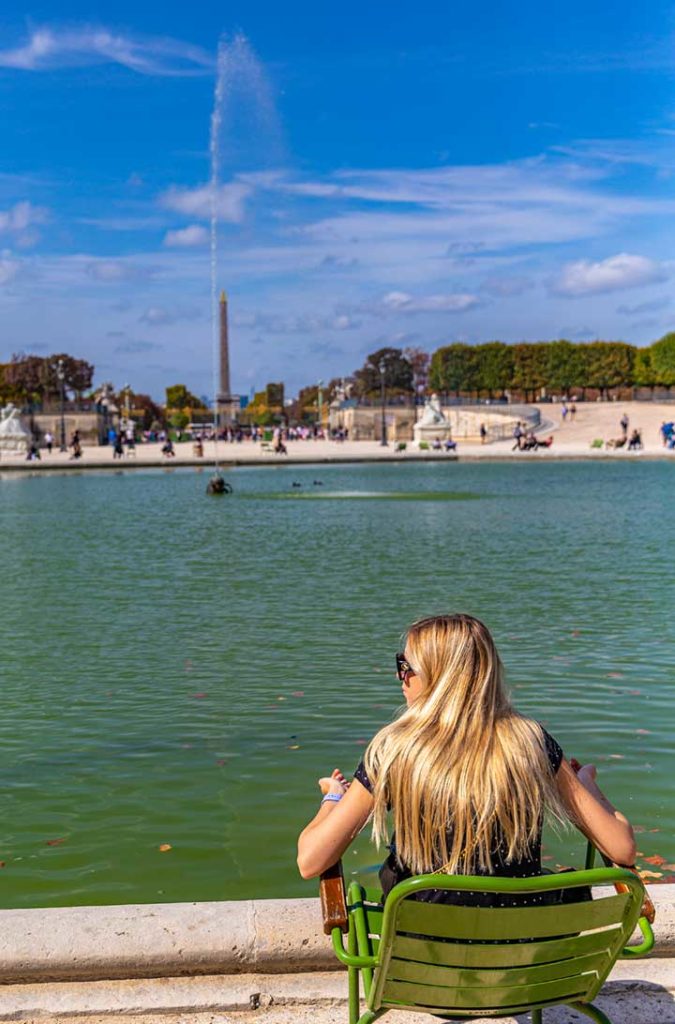 Mulher senta ao sol no Jardim das Tuileries, em Paris