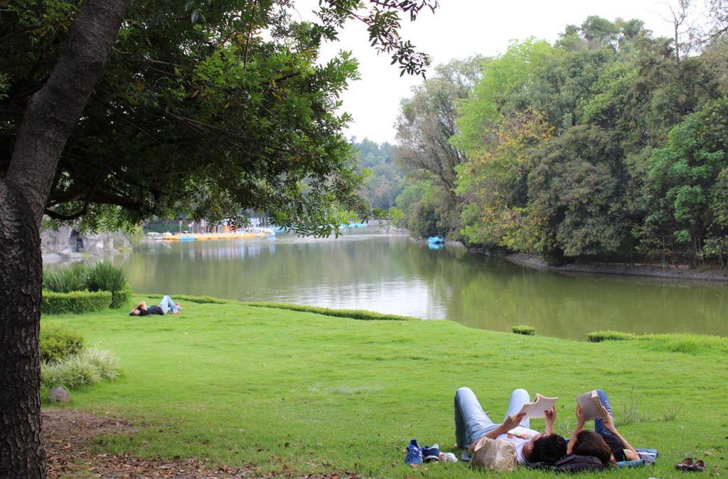 Casal deita na grama à beira de lago no Parque Chapultepec