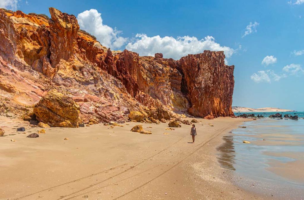 Mulher caminha próxima às falésias da Praia da Peroba, em Icapuí (Ceará)