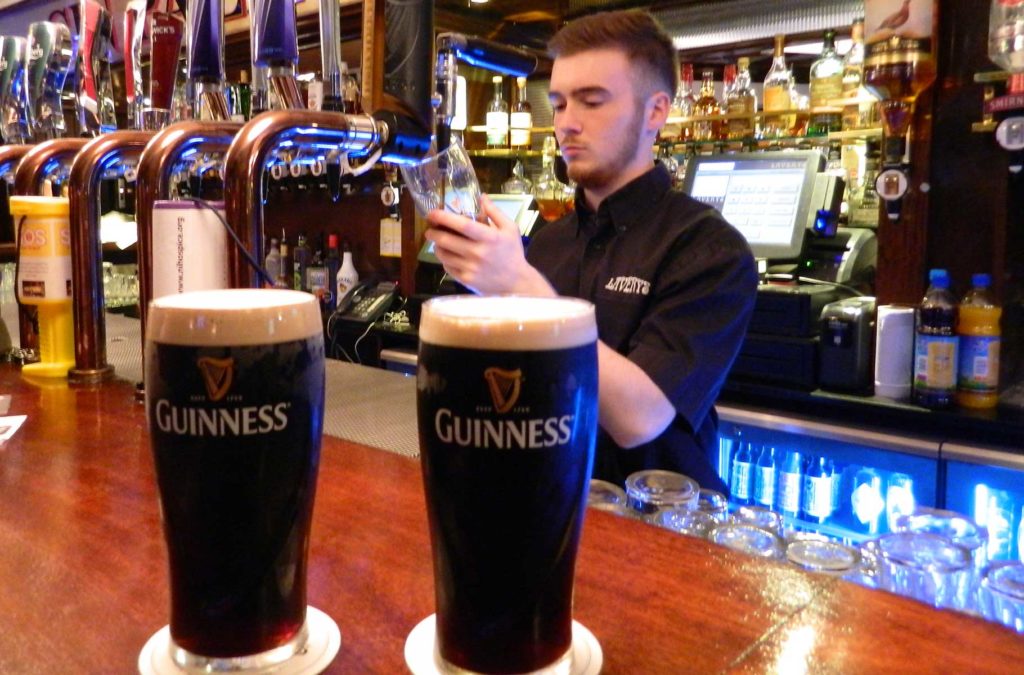Garçom serve cerveja Guinness em pub de Belfast, na Irlanda do Norte