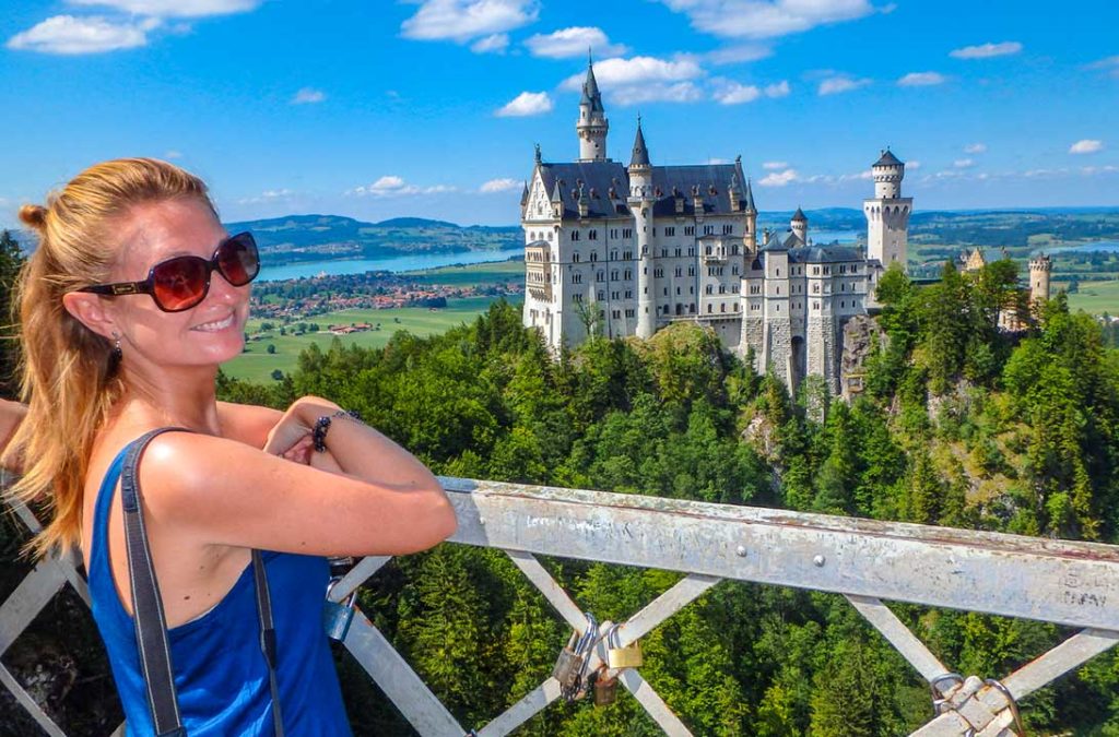 Mulher posa para foto na Ponte Marienbrücke, com o Castelo de Neuschwanstein ao fundo