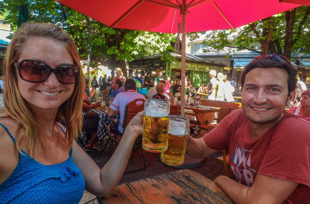 Casal brinda com canecões de cerveja no biergarten do Viktualienmarkt, em Munique