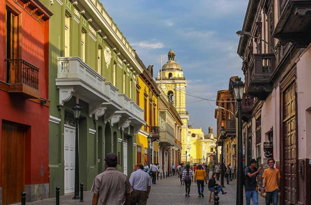 Pessoas caminham pelas ruas do centro histórico de lima ao entardecer