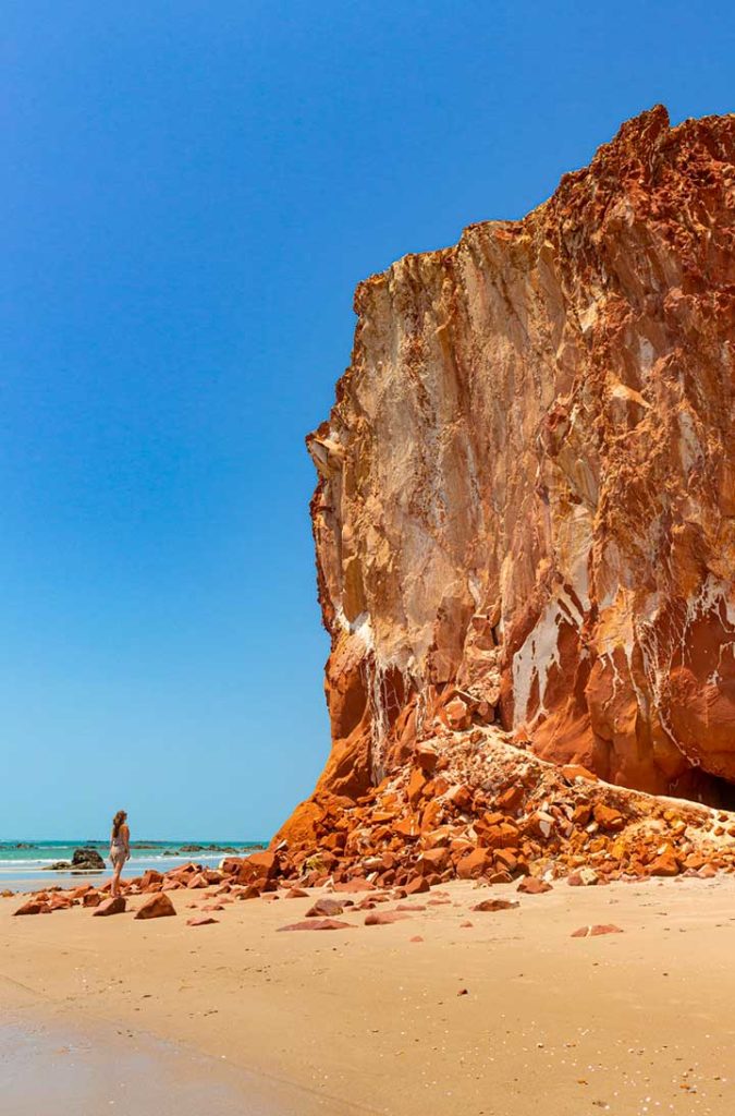 Mulher caminha próxima às falésias da Praia Redonda, em Icapuí (Ceará)