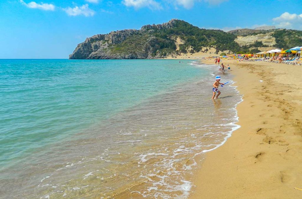 Criança foge de onda na beira da Praia de Faliraki, em Rhodes