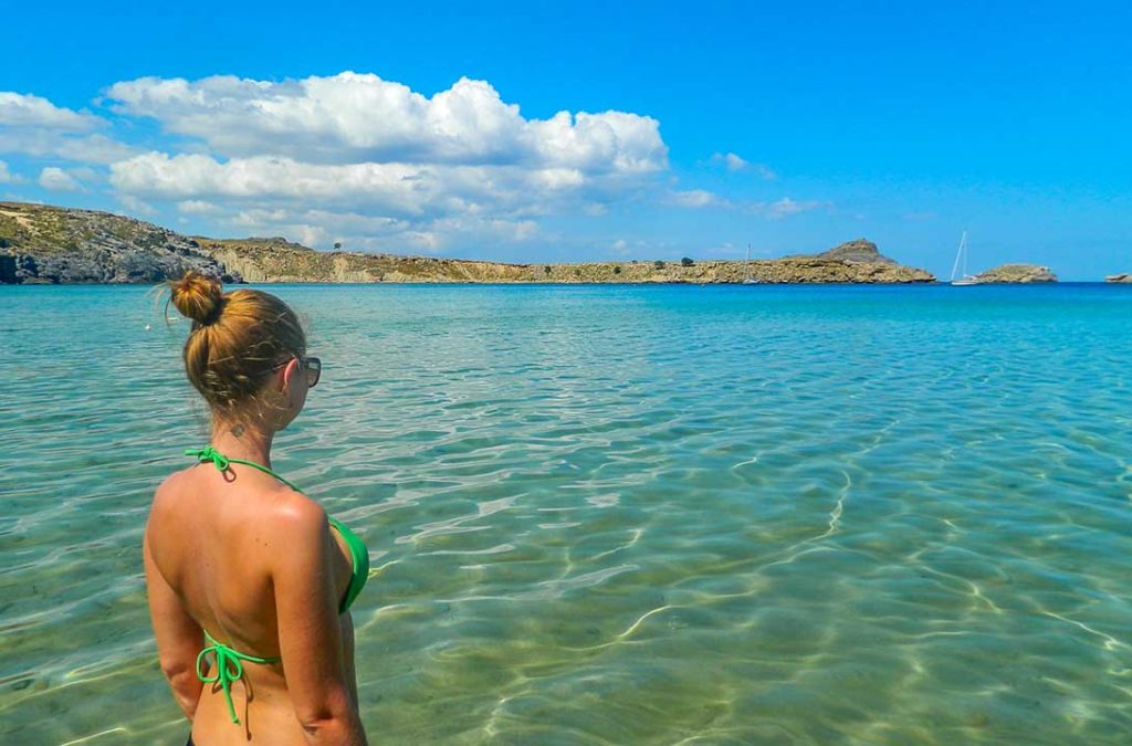 Mulher admira o mar cristalino da Praia de Lindos