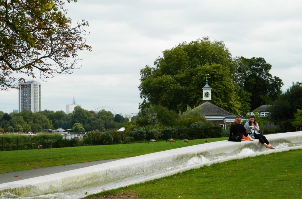 Mulheres sentam em mureta de fonte do Hyde Park, em Londres