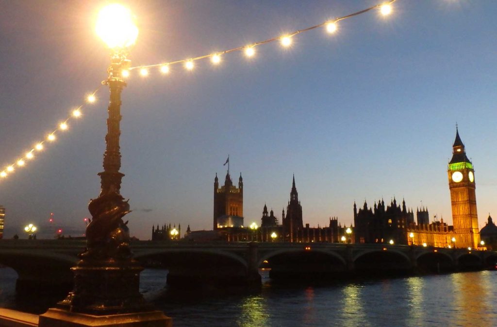 Luzes de lampiões se acendem com Parlamento britânico iluminado ao fundo