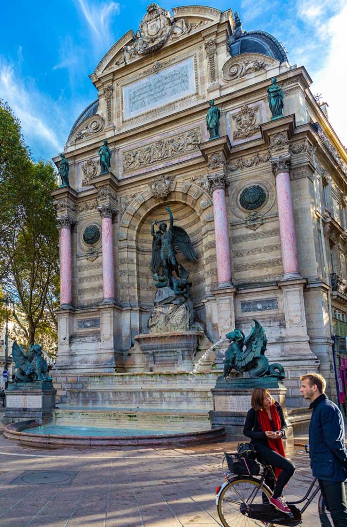 Casal conversa em frente à Fonte Saint-Michel, em Paris