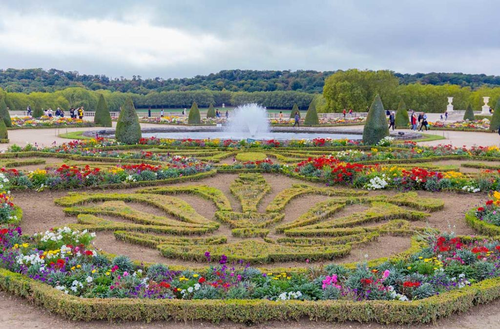 Canteiros floridos e fontes dos jardins do Palácio de Versailles