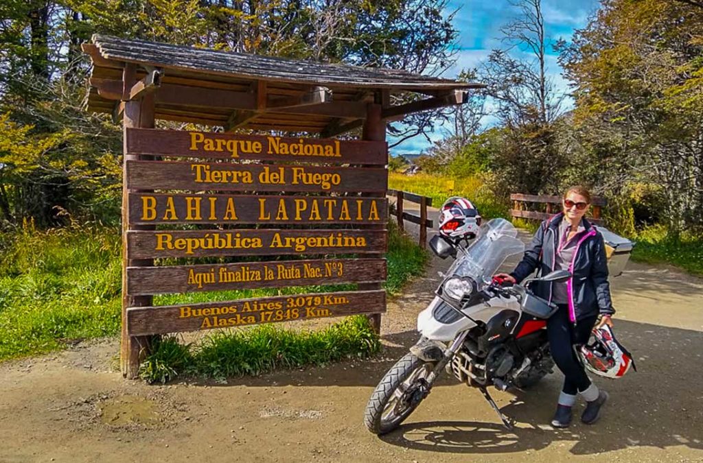 Mulher de moto posa para foto na placa que indica o fim da Ruta 3, no Parque Nacional Terra do Fogo