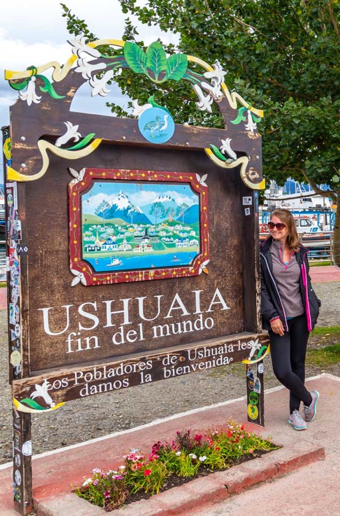 Mulher posa para foto com a placa que dá as boas-vindas ao 'fim do mundo'