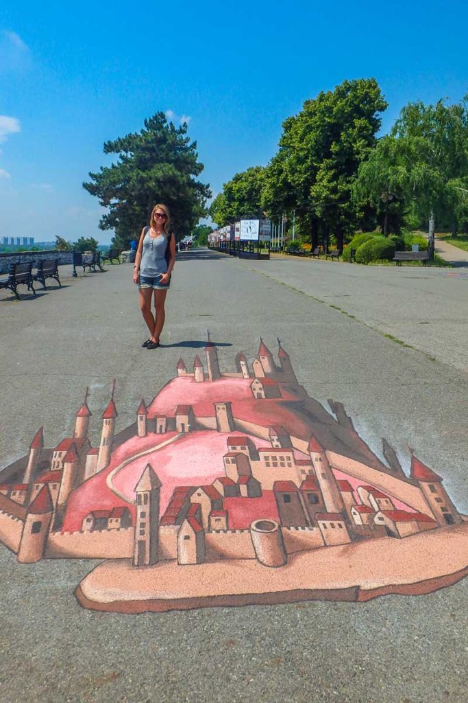 Mulher posa para foto com grafite feito no chão do Parque Kalemegdan