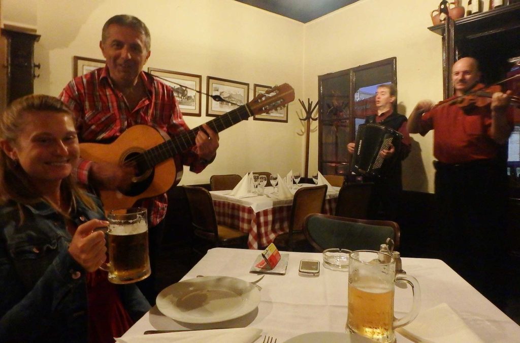 Músicos se apresentam para mulher em mesa da kafana '?', a mais antiga de Belgrado