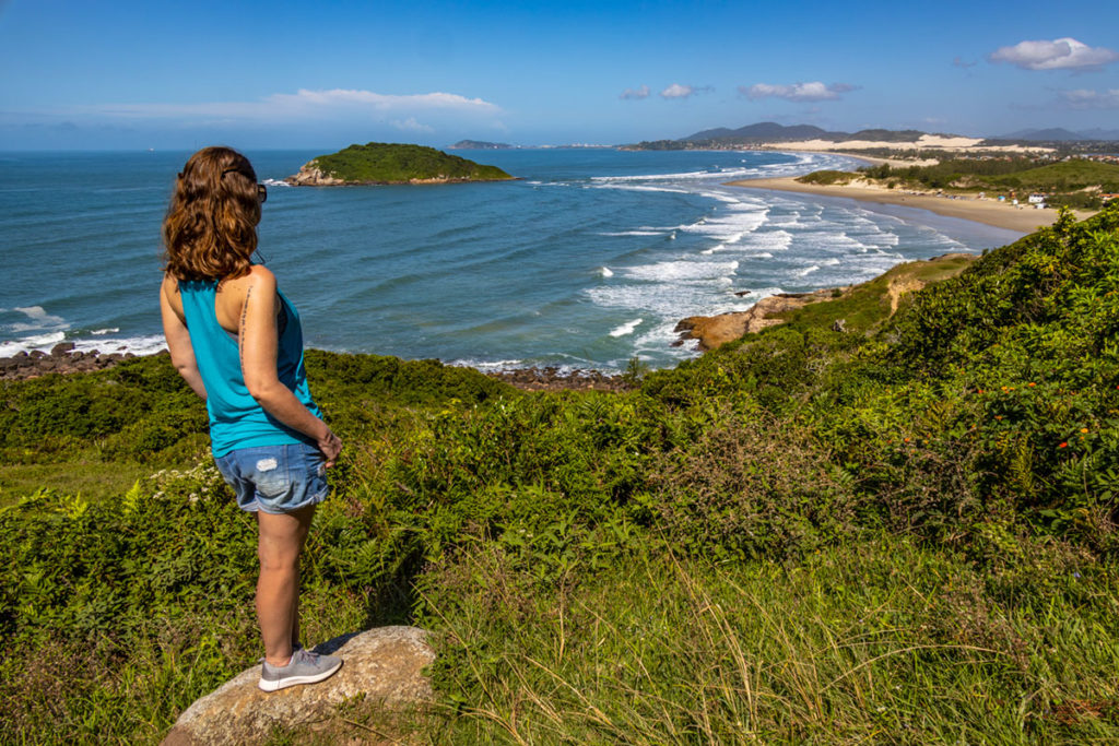 Mulher admira a vista da trilha entre as praias de Ibiraquera e do Rosa