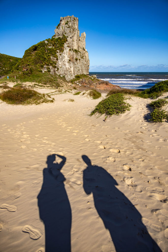 Sombra projetada na areia mostra casal fotografando a Pedra da Guarita, no parque do mesmo nome