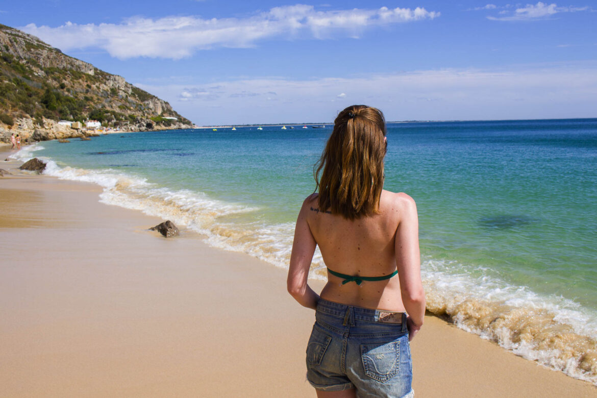 Mulher sozinha de costas admira a Praia de Galapinhos