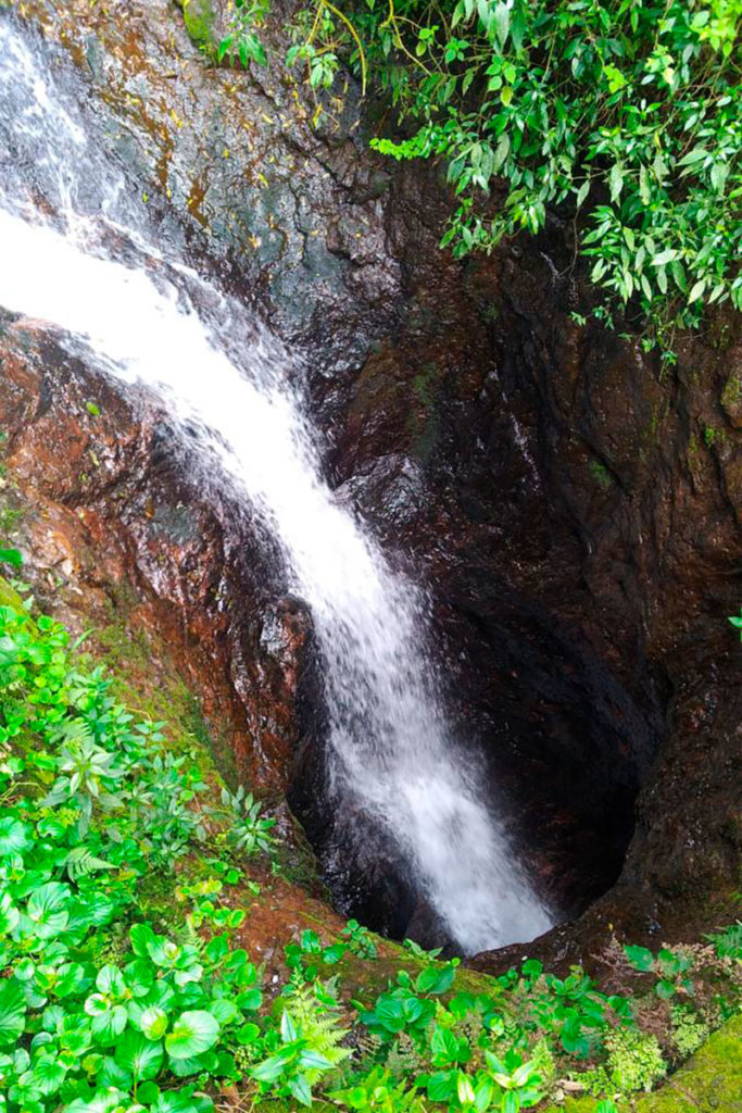 Água cai por buraco no chão e forma a Cascata Garganta do Diabo, em Vespasiano Corrêa