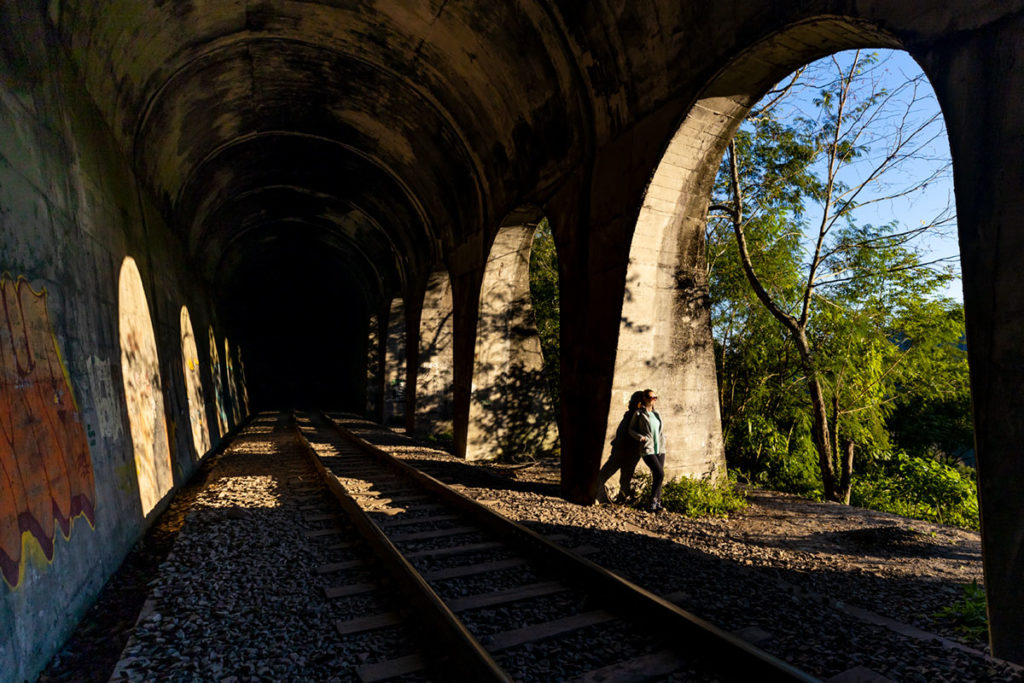Mulher posa para foto dentro de túnel vazado da Ferrovia do Trigo