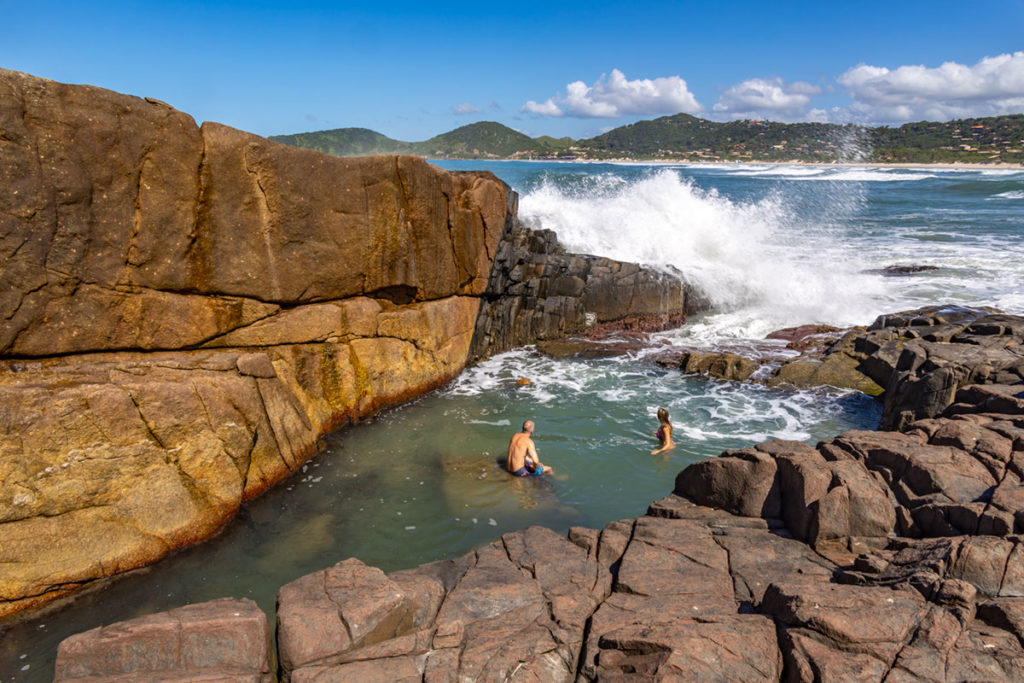 Casal toma banho na piscina natural da Praia do Rosa